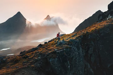 Foto op Aluminium Man climbing mountains traveling in Norway tourist solo hiking in Lofoten islands outdoor traveler with backpack active healthy lifestyle adventure summer vacations © EVERST