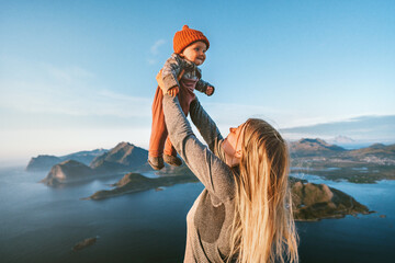 Mother lifting up infant baby family traveling in Norway summer vacations in Lofoten islands woman with child hiking in mountains healthy lifestyle outdoor love and happiness concept - 741701007