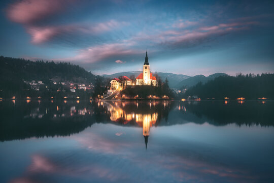 Assumption of Maria Church in the middle of lake Bled and illuminated cityscape at night, Bled, Slovenia