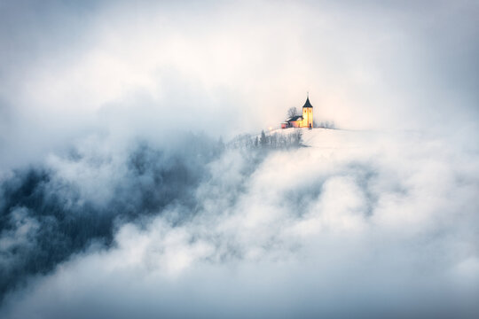 The Church of St Primoz and Felicijan on slopes of Velika Planina through the clouds, Jamnik, Kranj, Slovenia