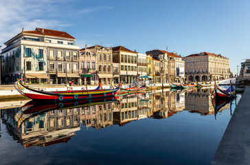 Reflexo da paisagem urbana da cidade de Aveiro nas águas da Ria de Aveiro. Barcos moliceiros na Ria