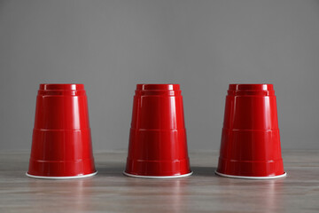 Shell game. Three red cups on wooden table