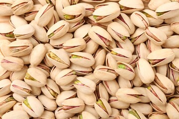 Tasty unpeeled pistachios as background, top view