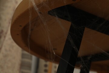 Old cobweb on wooden table indoors, closeup