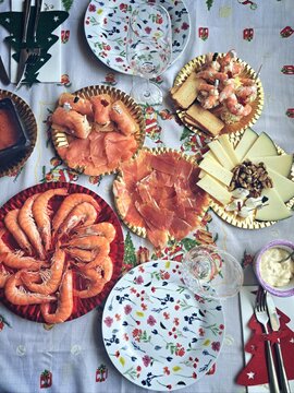 Overhead view of a Christmas buffet with prawns, cheese, smoked salmon, serrano ham and russian salad on a table