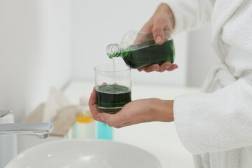 Young man using mouthwash in bathroom, closeup