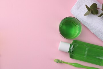 Flat lay composition with fresh mouthwash in bottle, glass and toothbrush on pink background. Space...