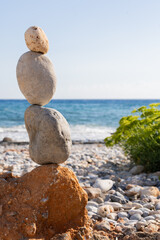 Close-up of stones stacked one behind the other in perfect balance forming a column next to a beautiful wild beach in the Aegean Sea south of the island of Crete