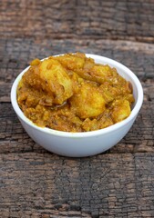 Closeup of Potato Dahi Curd Curry in a White Bowl Isolated on Textured Wooden Background