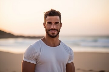 Portrait of handsome young man smiling on the beach at sunset.