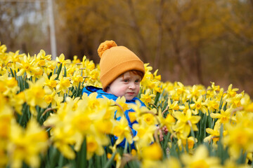 A red-haired boy rests in his grandmother's garden in the village among daffodils