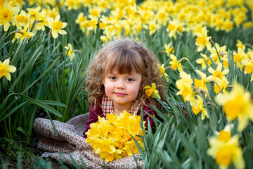 Curly girl holding a bouquet of yellow daffodils in the garden