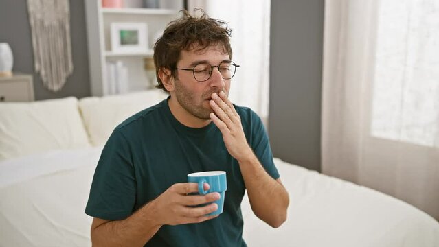 Shock explosion, young hispanic man, covering mouth after drinking coffee in bedroom, surprised and afraid after a gaffe