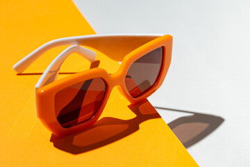 Minimal style composition made of trendy sunglasses closeup on orange and white sunlit background