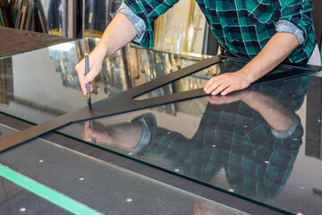 A glazier cuts glass in a glass factory, cutting thick glass, Professional glass equipment,...