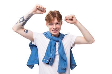 young positive red-haired man with a short haircut with a tattoo on his arms wearing a white t-shirt