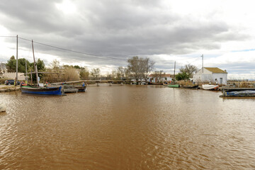Fototapeta na wymiar Rustic Riverside Scene with Moored Boats and Cloudy Sky
