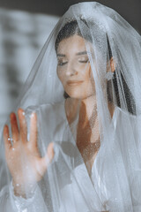 portrait of an incredibly beautiful girl bride in a white robe in the bedroom, the bride poses...