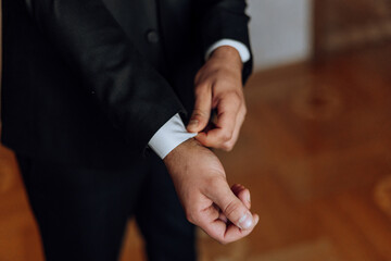 young smiling man buttoning up his jacket in the morning before the wedding. close-up of a man in a business suit. Businessman puts on a suit. A man fastens the buttons on his jacket.