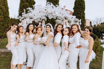 Wedding photography. The bride in a wedding dress and her friends in white dresses pose with...