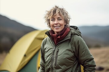 Portrait of happy senior woman standing in front of tent at campsite