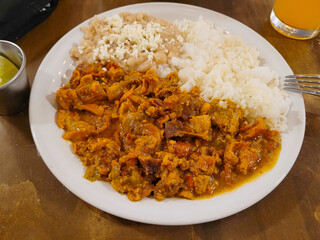 Hearty plate of Chicharron in Red Sauce accompanied by white rice and beans, food