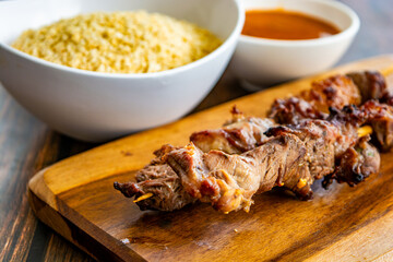 brazilian espetinho de carne (meat on a skewer), with farofa and pepper sauce. traditional food also known as 'espetinho de gato'