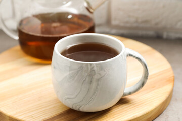 Aromatic tea in cup and glass teapot on table, closeup