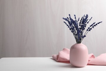 Bouquet of beautiful preserved lavender flowers on white wooden table near grey wall, space for text