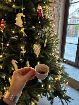 cup of coffee in hand and Christmas tree