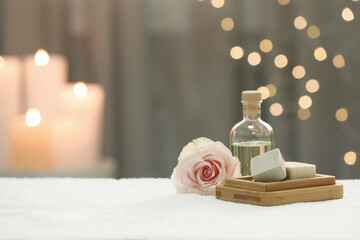 Obraz na płótnie Canvas Beautiful spa composition with essential oil, soap bar and rose on white towel against blurred background. Space for text