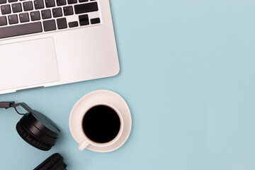 Headphones, cup of black coffee and laptop on a blue background. Online work concept with place for...