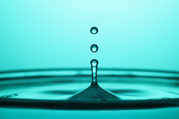 Splash of clear water with drops on turquoise background, closeup