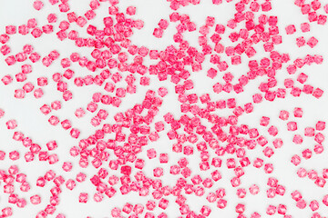 Texture made from pink square acrylic beads scattered on a blue background.