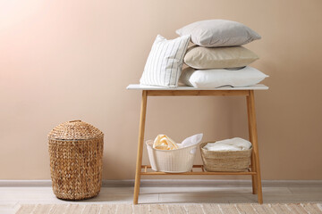Soft pillows and laundry baskets near beige wall indoors