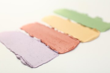 Samples of different color correcting concealers on white background, closeup
