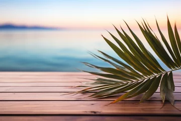 Photo sur Plexiglas Descente vers la plage Palm leaf on wooden table with blurred beach and ocean in the background
