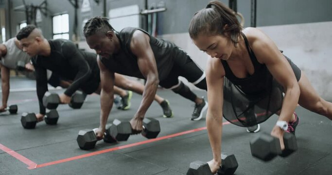 People, push ups and dumbbells in weightlifting training for workout, exercise or team in practice at gym. Group lifting body weight for strong arms or performance at indoor health club together
