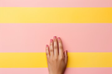 A beautiful woman hand with a pink manicure and a white french on a bright yellow-pink background