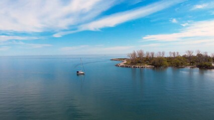 Solitary boat gently floats lake near small island, essence perfect nature retreat. serene tranquil setting embodies peaceful nature retreat, ideal quiet relaxation. natural surroundings. Drone view.