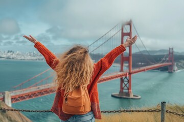 A woman stands with raised arms on a hill overlooking the Golden Gate Bridge. - Powered by Adobe