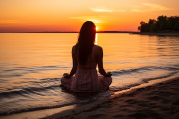 Fototapeta na wymiar Woman in dress sitting on beach at sunset