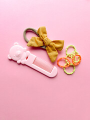 A set of accessories for a little girl on a pink background. Hairpins, comb, hair bands....