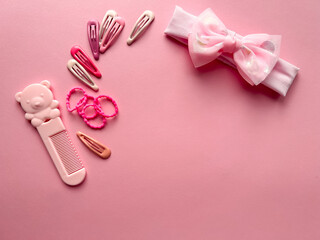 A set of accessories for a little girl on a pink background. Hairpins, comb, hair bands. Fashionable hair accessories for little girls. Flat styling. Top view