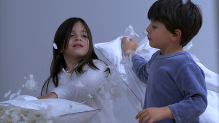Small brother and sister having pillow fight with feathers flying everywhere captured in super slow...