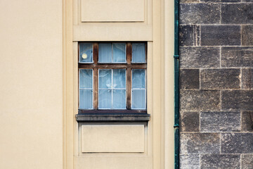 Rectangular window with a wooden frame against a background of a beige wall and a gray stone wall. From the series window of the World.