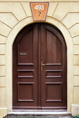 Brown wooden door with an arch against a yellow wall. From the series doors of the World.