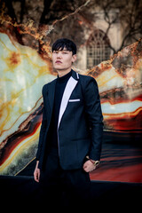 Oriental, asian handsome man model stands on abstract background. Fashion