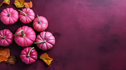 A group of pumpkins with dried autumn leaves and twig, on a magenta color stone