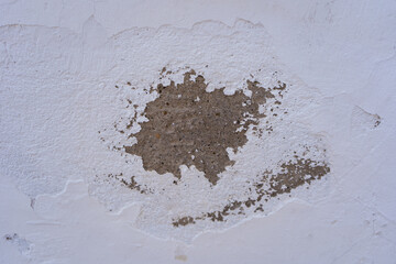 Old light wallpaper wall background, white peeling plaster, textured putty. Dark spot on grunge...